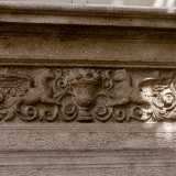 Assieme a loro saliamo gli scalini che conducono al portone d�ingresso e guardiamo pi� da vicino i bassorilievi che si ripetono su tutto il prospetto dell�abitazione: cornici rettangolari adornate con altri leoni alati che sorreggono una cornucopia